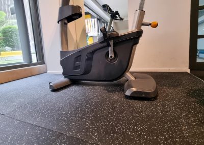 Image shows a exercise bike resting on new rubber gym mats, installed in an apartment gym in auckland.