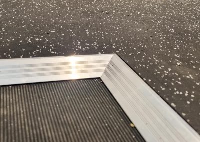 Image shows metal transition strips that form a seamless transition between existing flooring and new rubber matting.